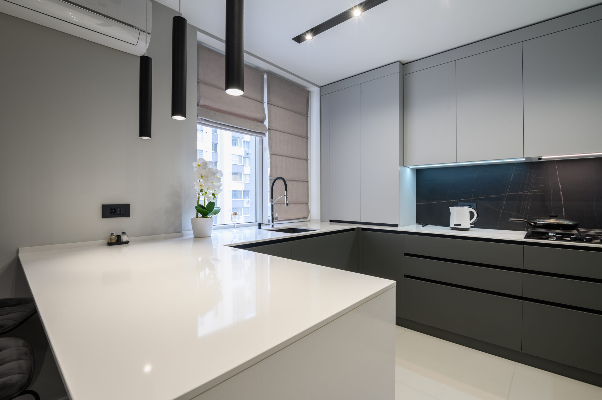 Elegant white and grey luxury kitchen, dining room with kitchen bar and stools in studio apartment interior