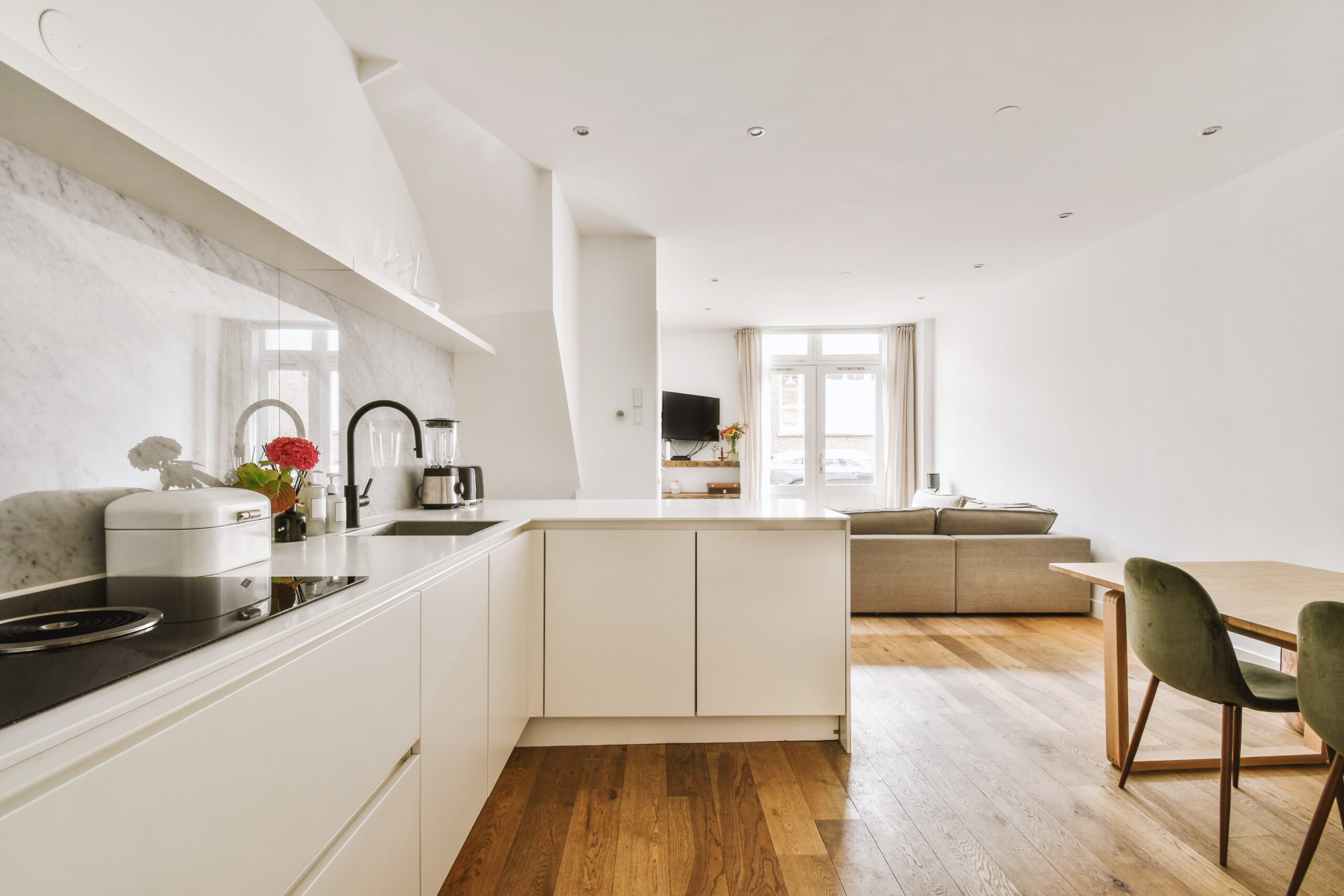 Fragment of interior of light narrow home kitchen with minimalist style white furniture with sink and stove
