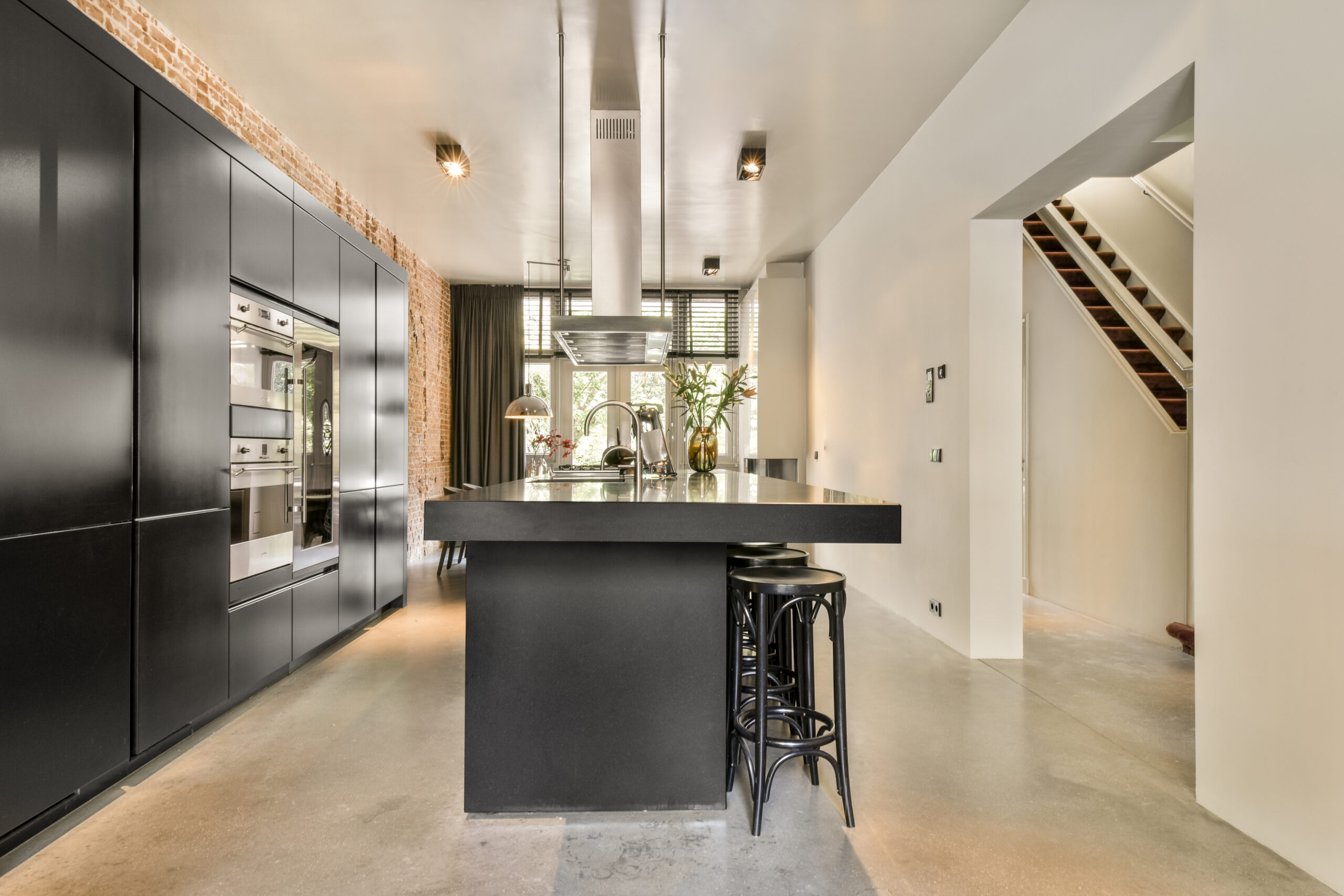Contemporary minimalist style interior design of light studio apartment with wooden table and chairs in dining zone between open kitchen and living room with white walls and parquet floor
