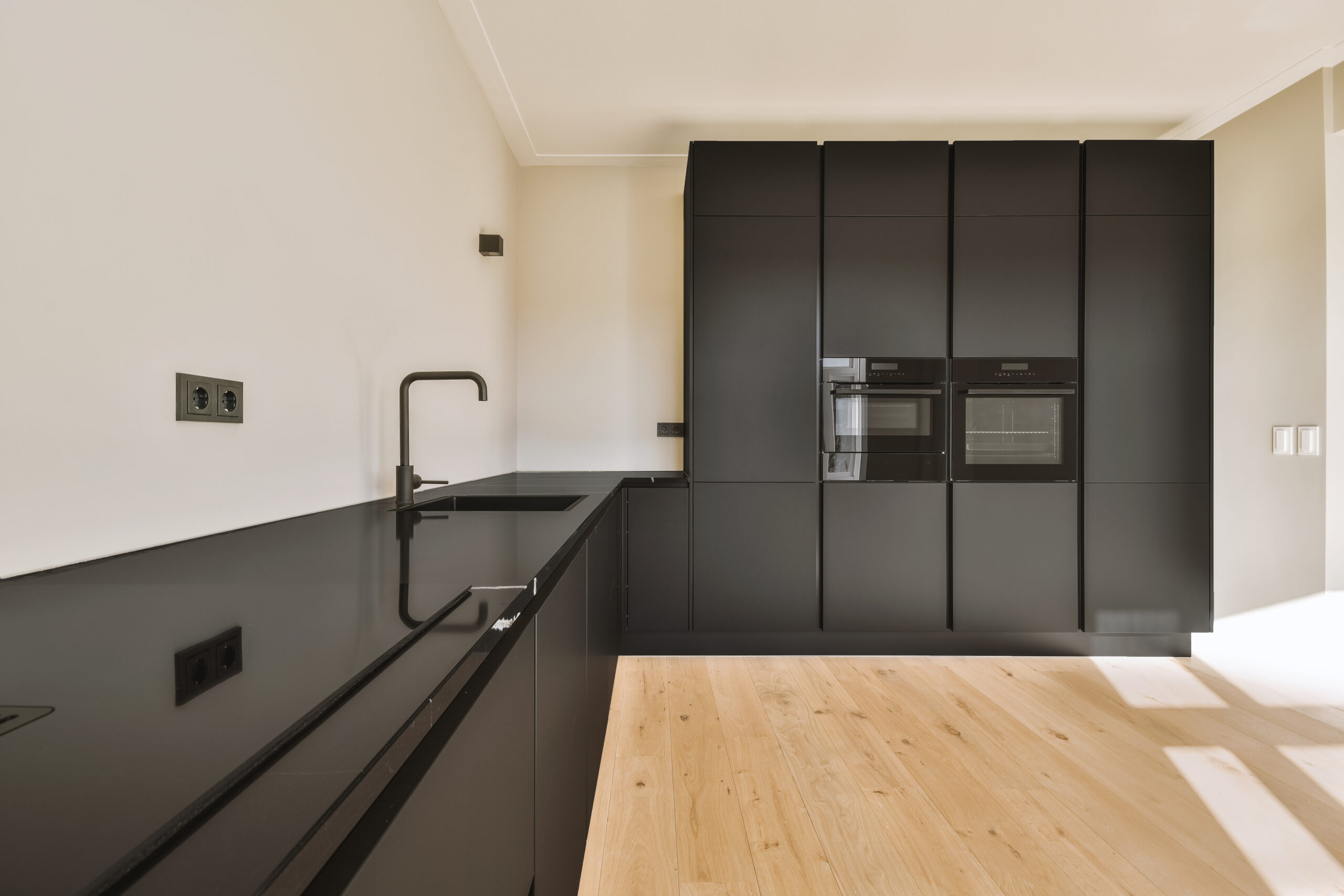 Interior of empty white kitchen with windows and wooden parquet floor