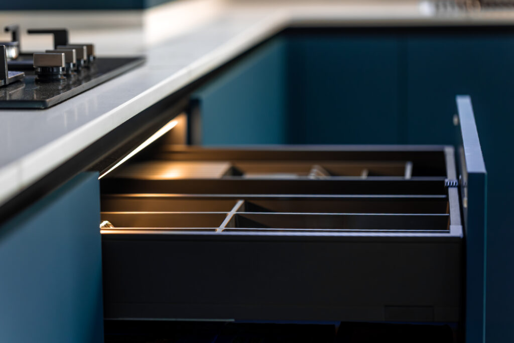 Corner drawer with a cutlery organizer and soft LED strip beneath a quartz countertop. Handleless matte blue cabinetry delivers a premium minimalist look with smart storage. SSUCv3H4sIAAAAAAAAA41Py47DIAz8F5+JBEmaCn6l6oGAm1pNQgWm1Sri31ekqfa6txnb8/AG5MGA94M6oZPNudNDo9RNNtr250behhHH1ivdIgjwlhGM6jqtVdv3J627XkopBYw2kQOzAc1zThwtU1jBSAERV49xh+iJQyQ7g5FFQGLLOWECsxUBzjJOIdLOv36Xrc7BAAhIeaygiH/OrgLshKv7qf6lFpnR7nGXq4DHmzEuR3bge61Y4TOSo3U6OuXEYfngNXDV7gkc3IP8If68cafEIdYsyM85WI/+WOdxIeYvjfgifP9dl1J+AYrMfLeEAQAA