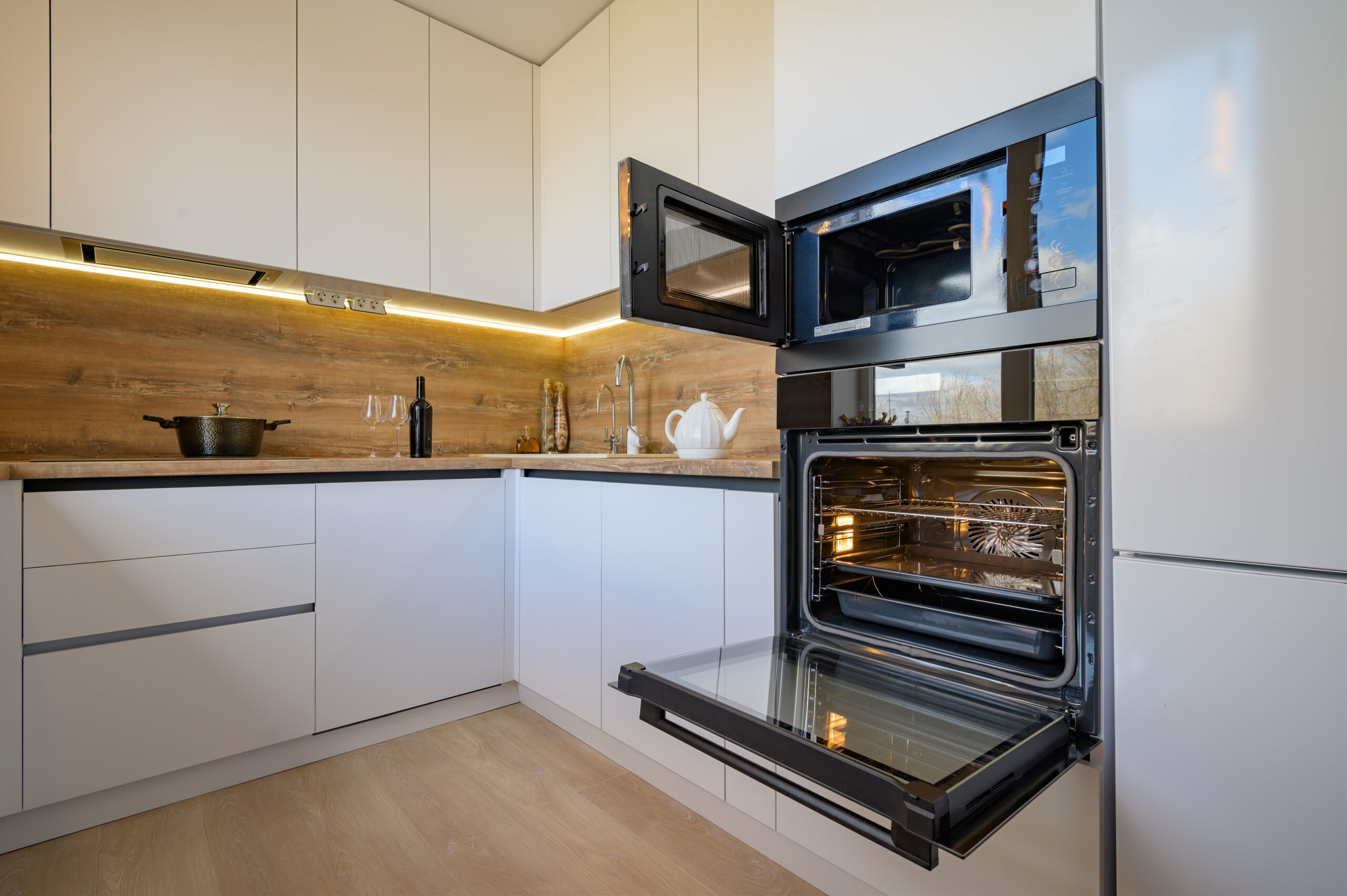 Well designed white and wooden beige modern kitchen interior with oven door opened