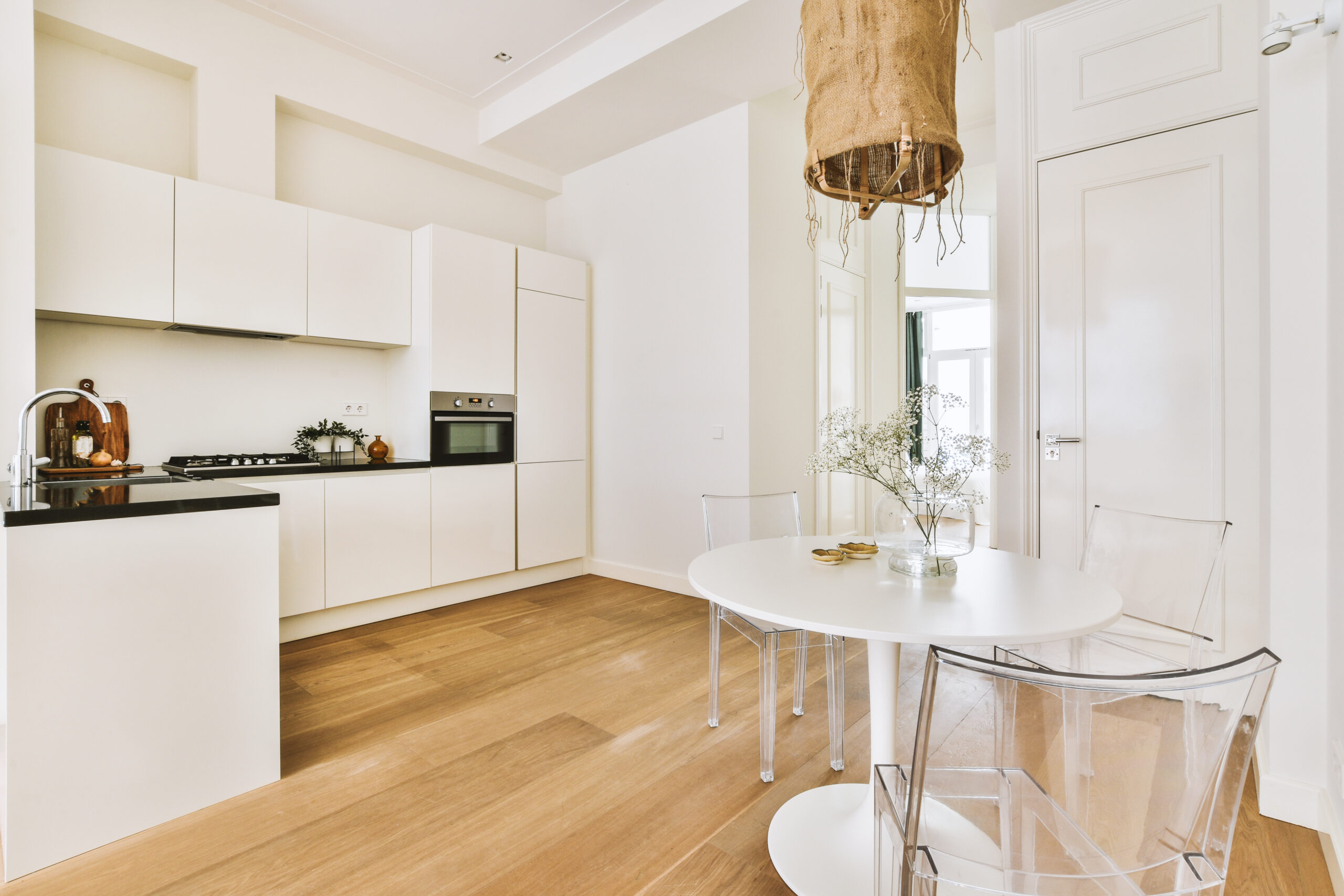 Fragment of interior of light narrow home kitchen with minimalist style white furniture with sink and stove