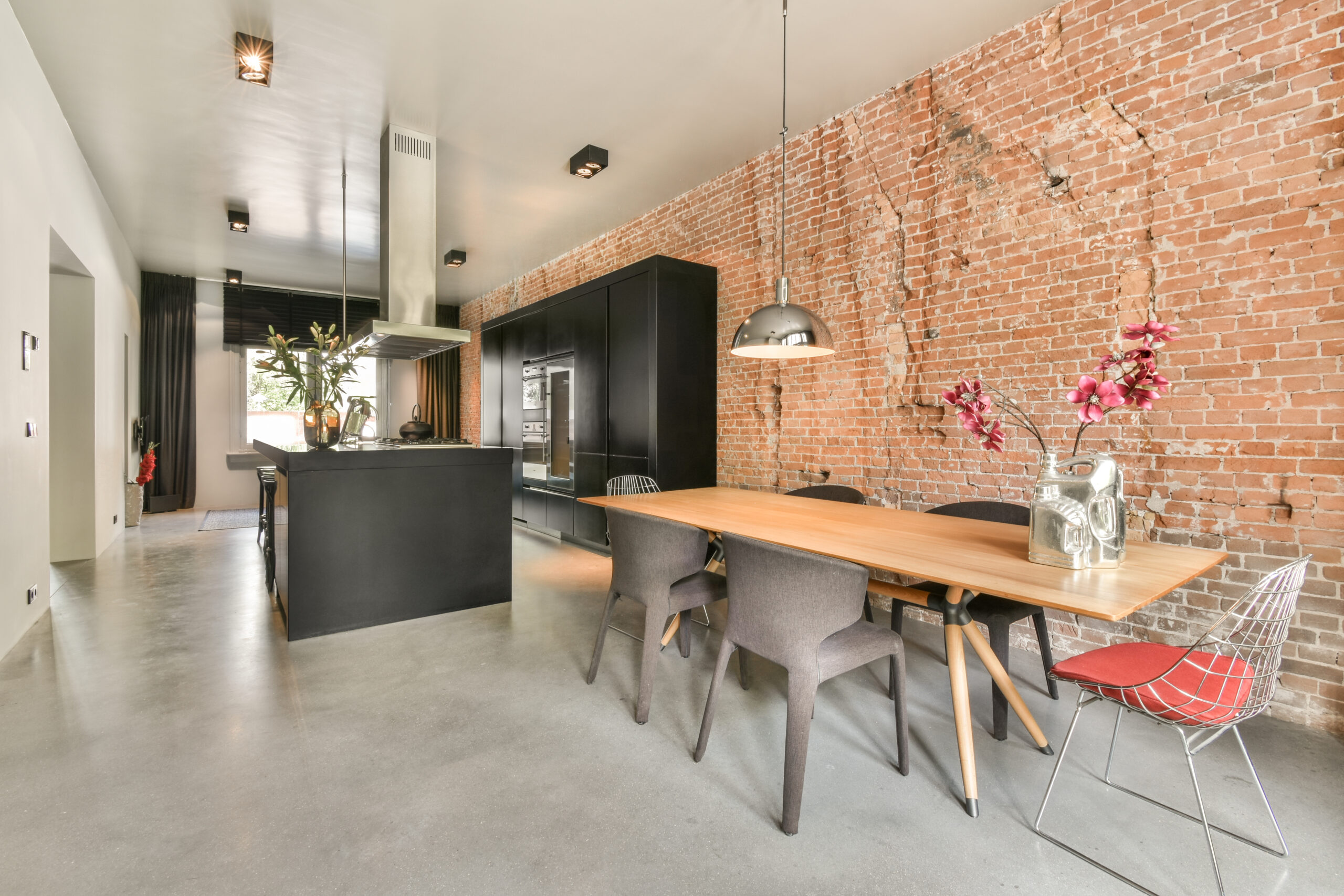 Contemporary minimalist style interior design of light studio apartment with wooden table and chairs in dining zone between open kitchen and living room with white walls and parquet floor