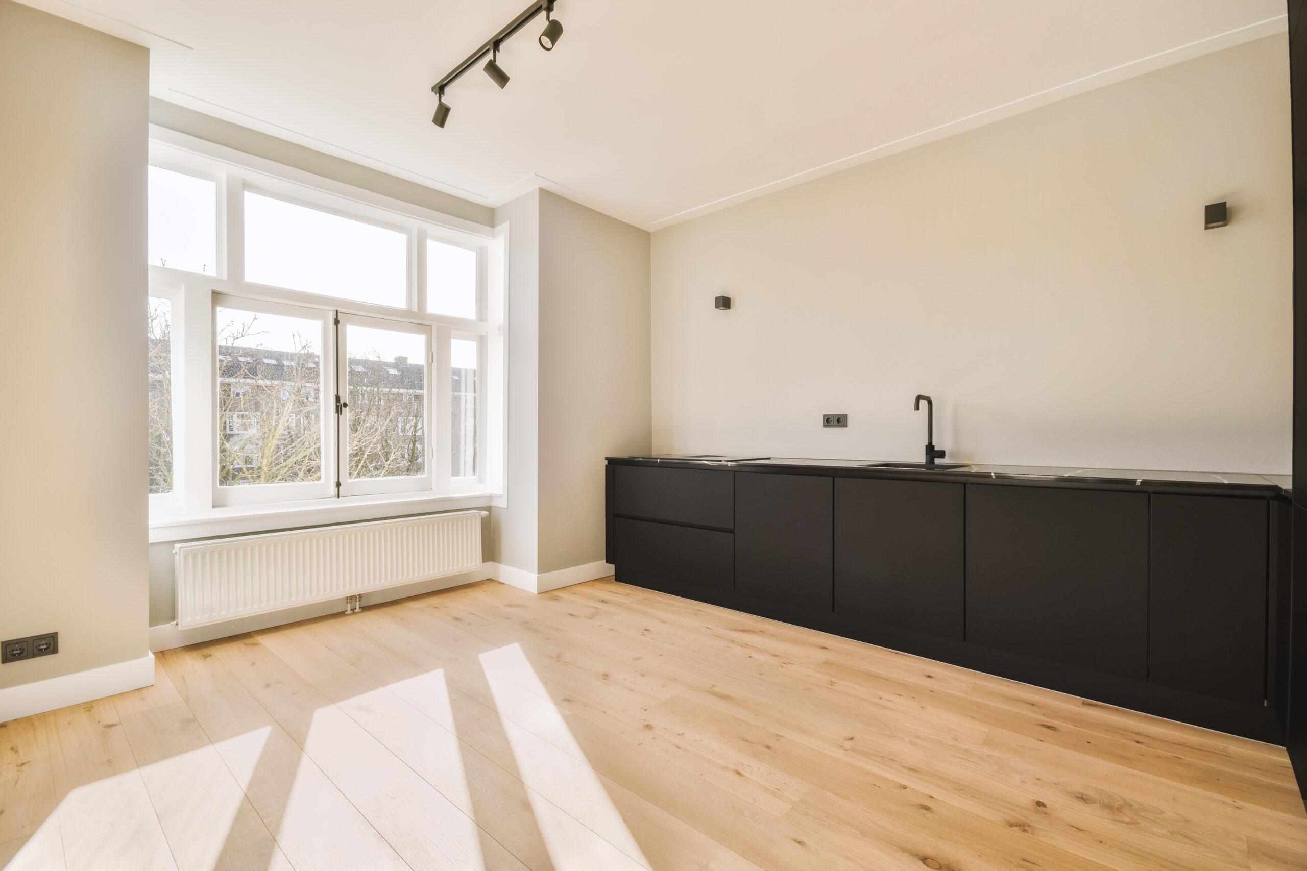 Interior of empty white kitchen with windows and wooden parquet floor