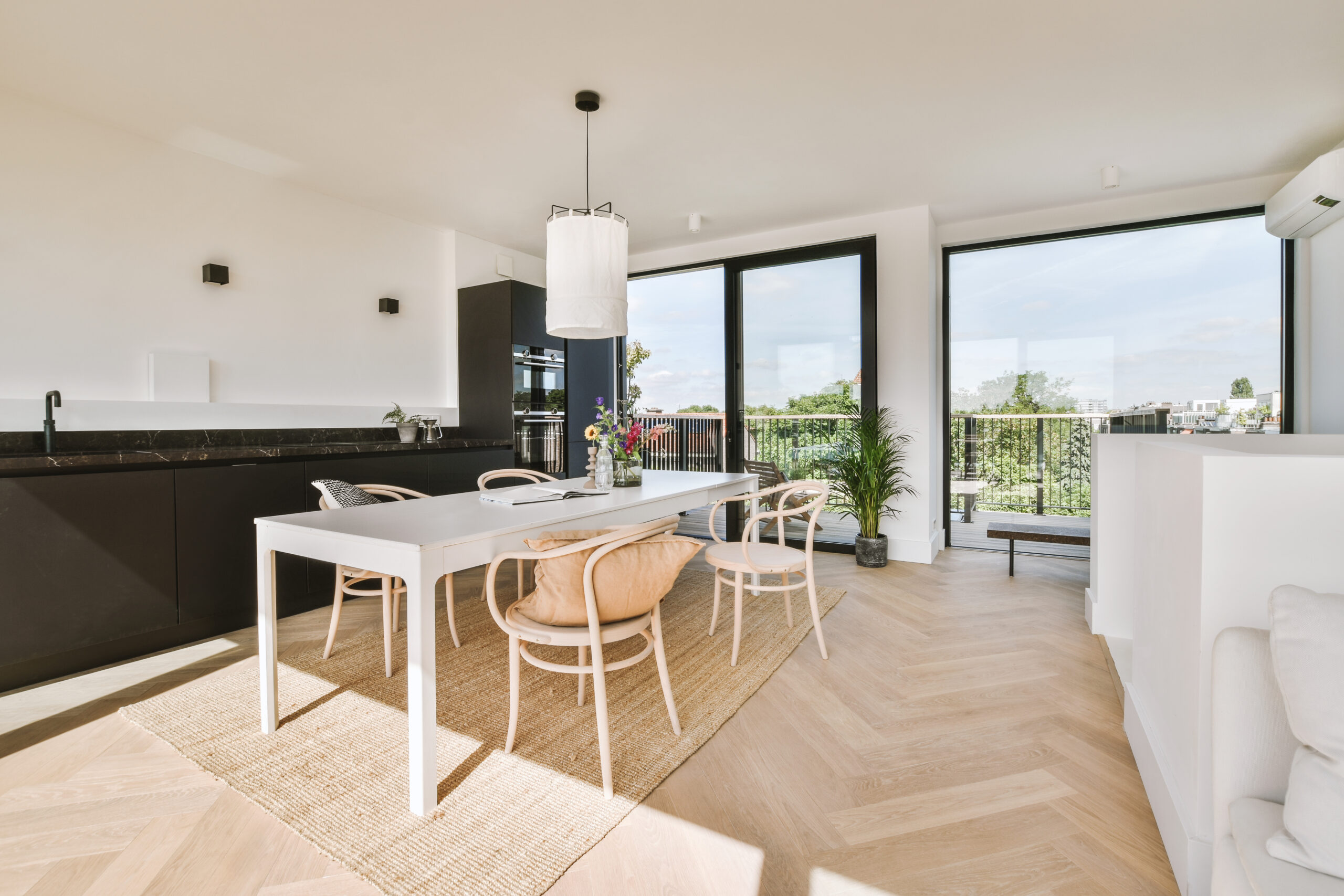 Home interior design of modern loft apartment with open kitchen in minimalist style and spacious dining zone with table and chairs