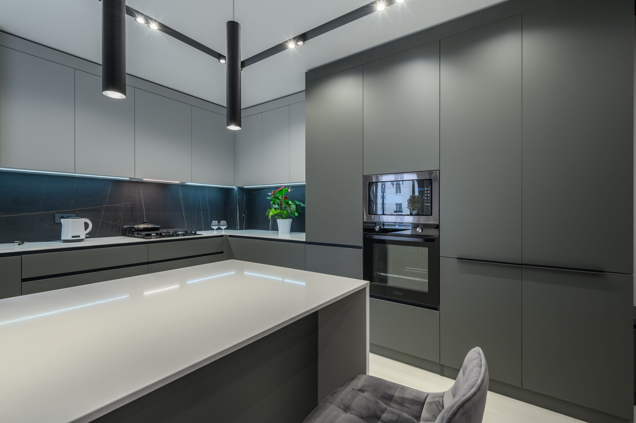 Elegant white and grey luxury kitchen, dining room with kitchen bar and stools in studio apartment interior