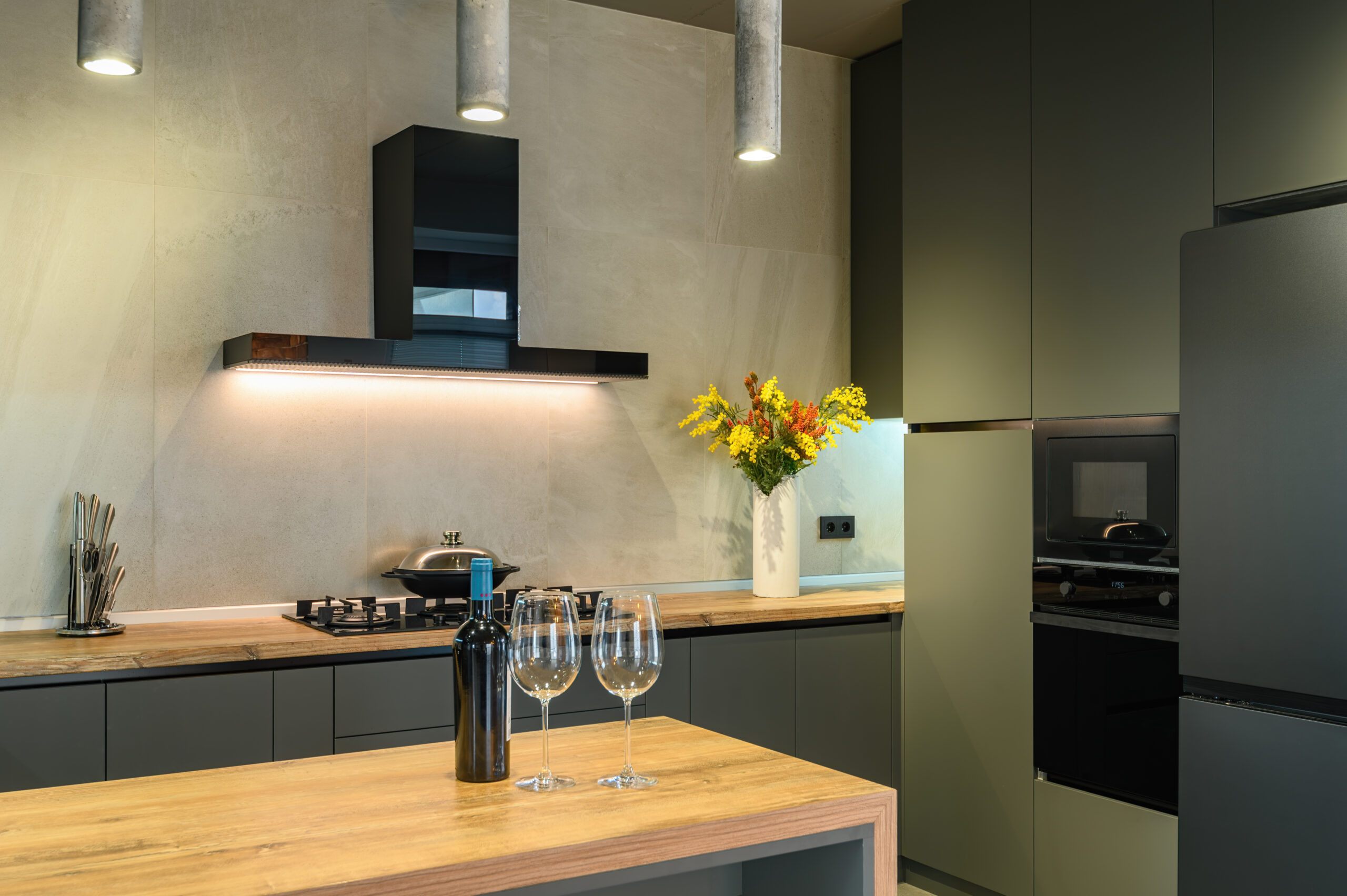Modern large luxury dark gray kitchen closeup with wine bottle at kitchen counter, low key