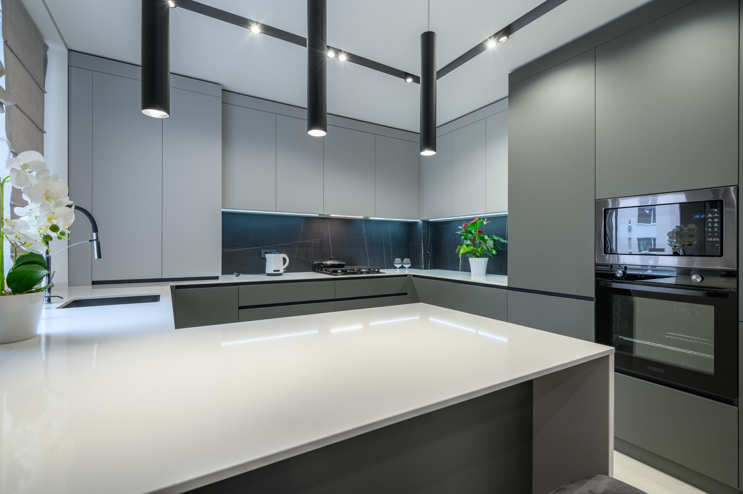 Elegant white and grey luxury kitchen, dining room with kitchen bar and stools in studio apartment interior