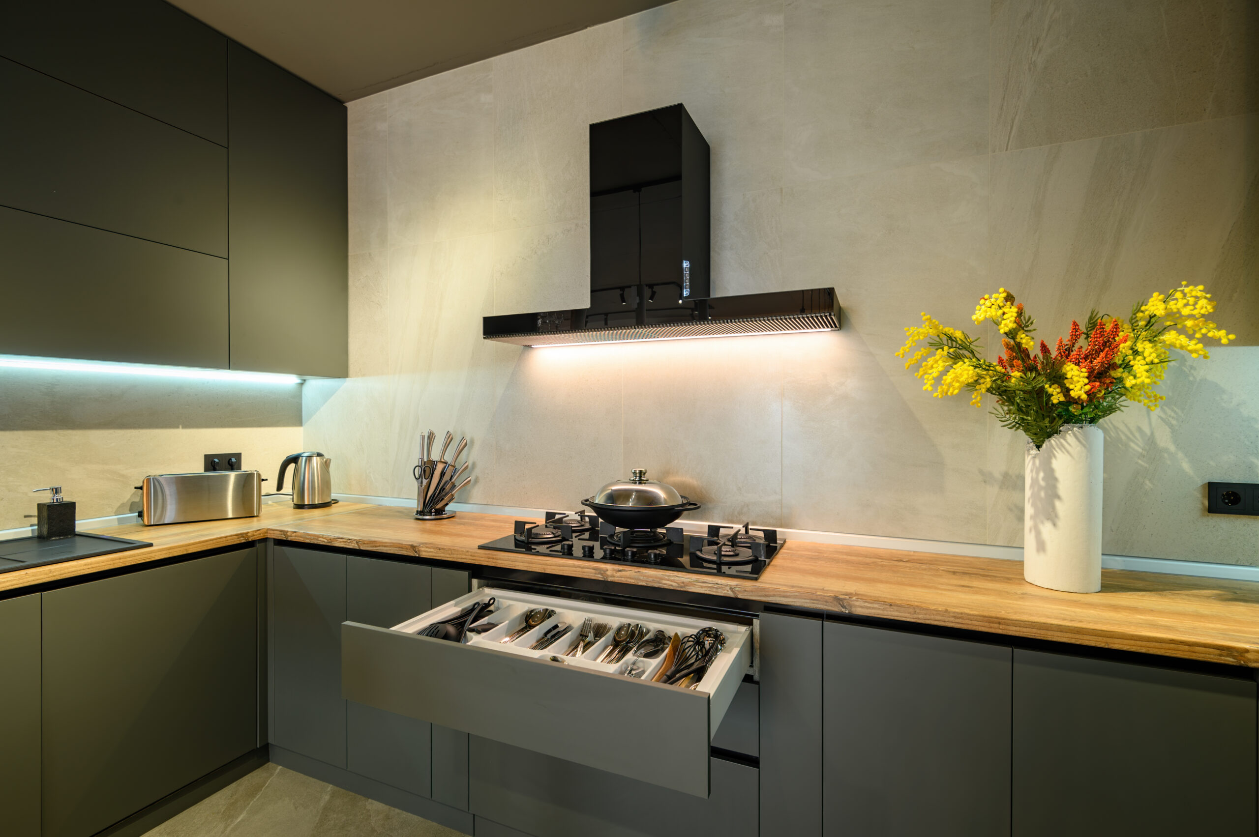 Modern large luxury dark gray kitchen, pulled out drawer with kitchen utensils