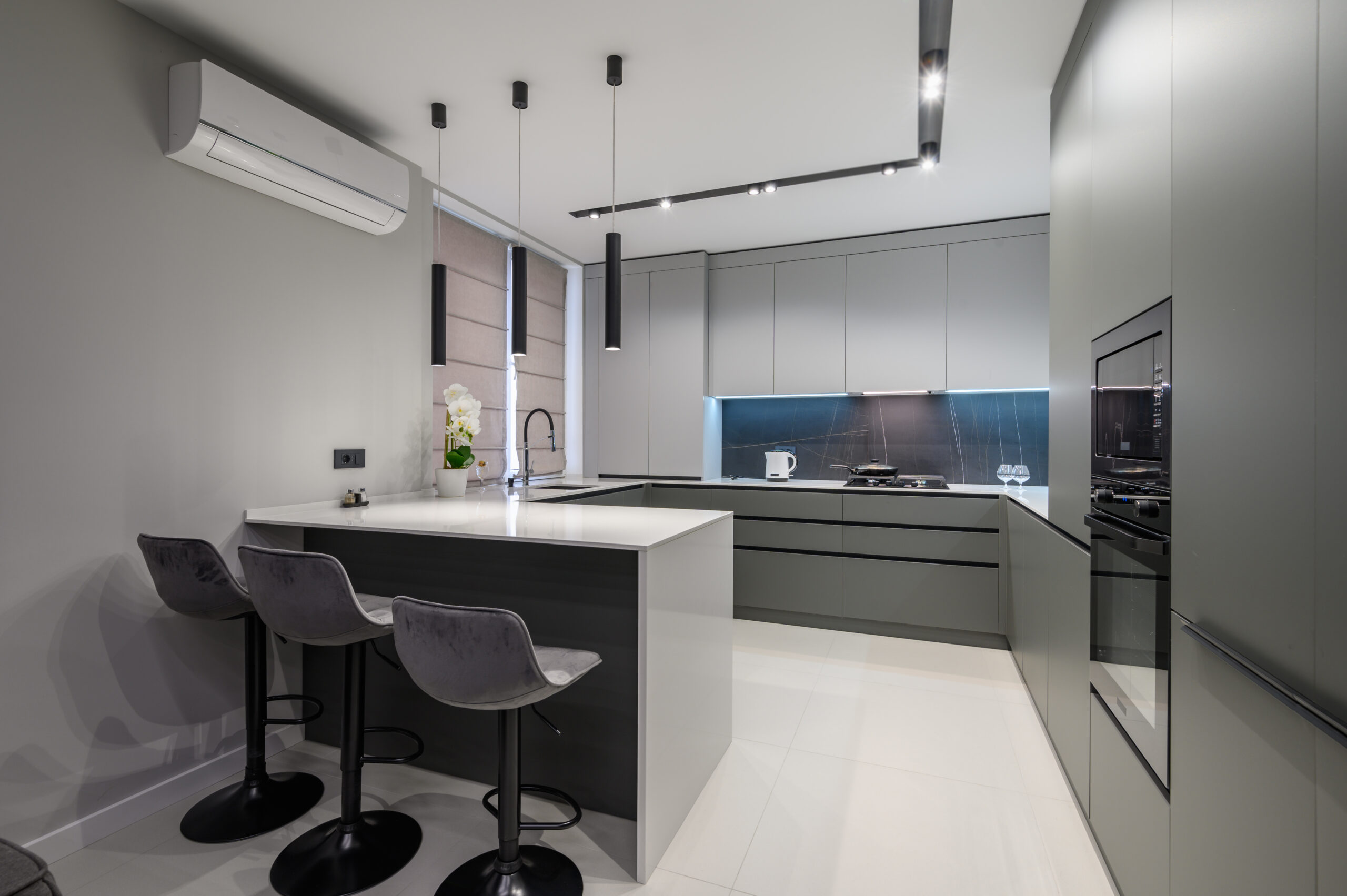Elegant white and grey luxury kitchen, dining room with kitchen bar and stools in studio apartment interior